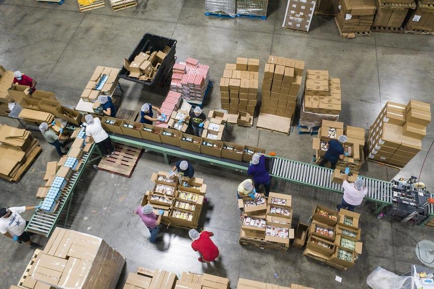 Warehouse floor seen from above: cartons, pallets and workers packing goods